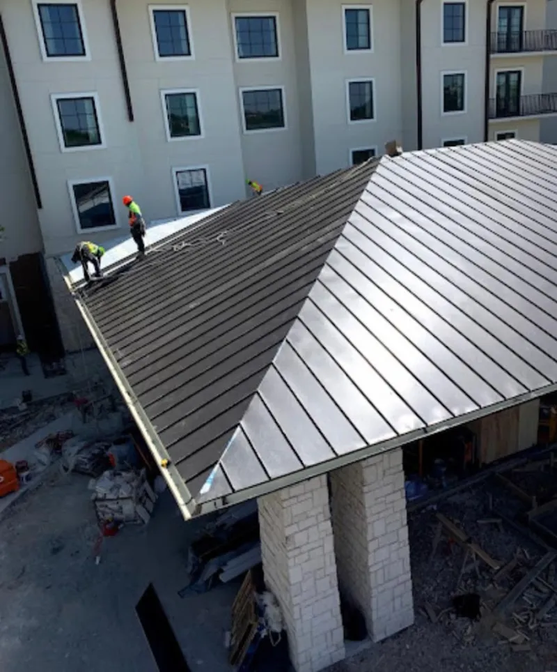 Crew installing standing seam metal roof panels on a commercial project in Mission